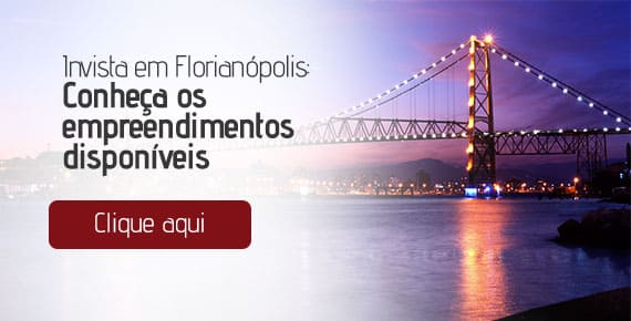 Ponte Hercílio Luz, em Florianópolis, iluminada a noite. O texto à esquerda "Invista em Florianópolis: Conheça os empreendimentos disponíveis. Clique aqui"
